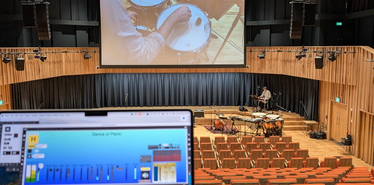 auditorium, showing laptop with max patch, audience interface, percussion, and a projected view of two drums