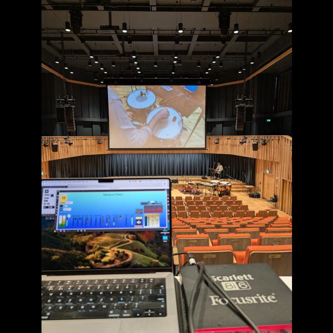 auditorium, showing laptop with max patch, audience interface, percussion, and a projected view of two drums