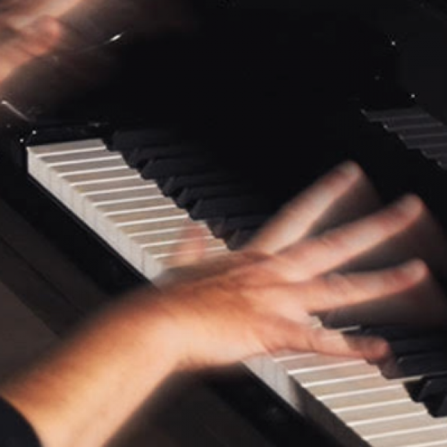 photo of piano keyboard with two hands held above the keys